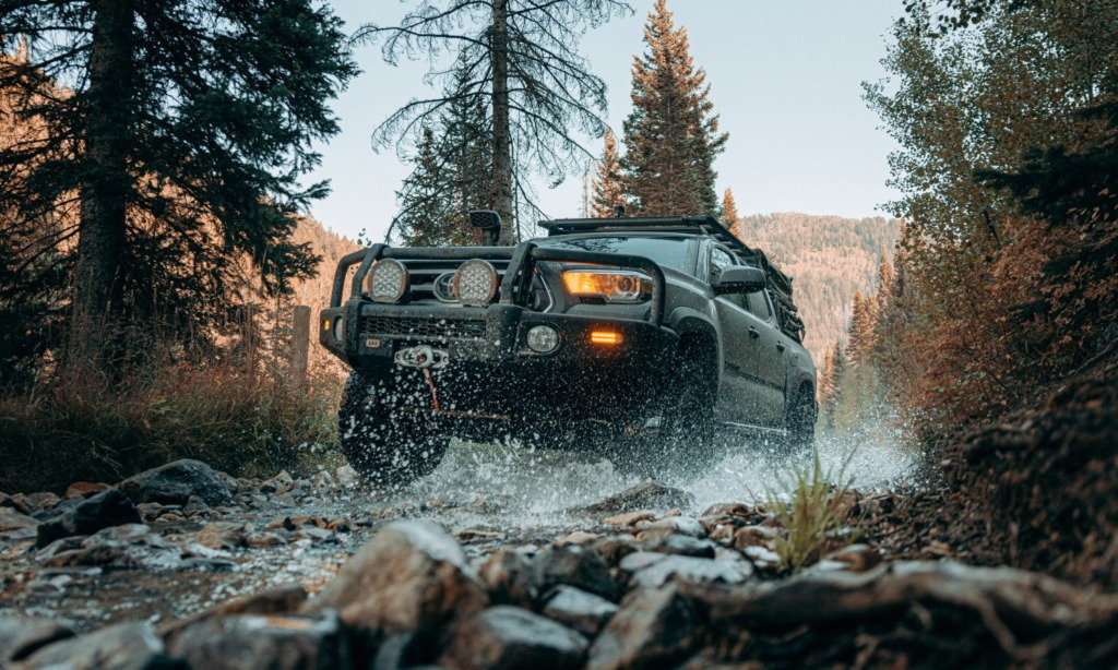 Overland Tacoma with winch bumper and roof rack crossing a mountain creek